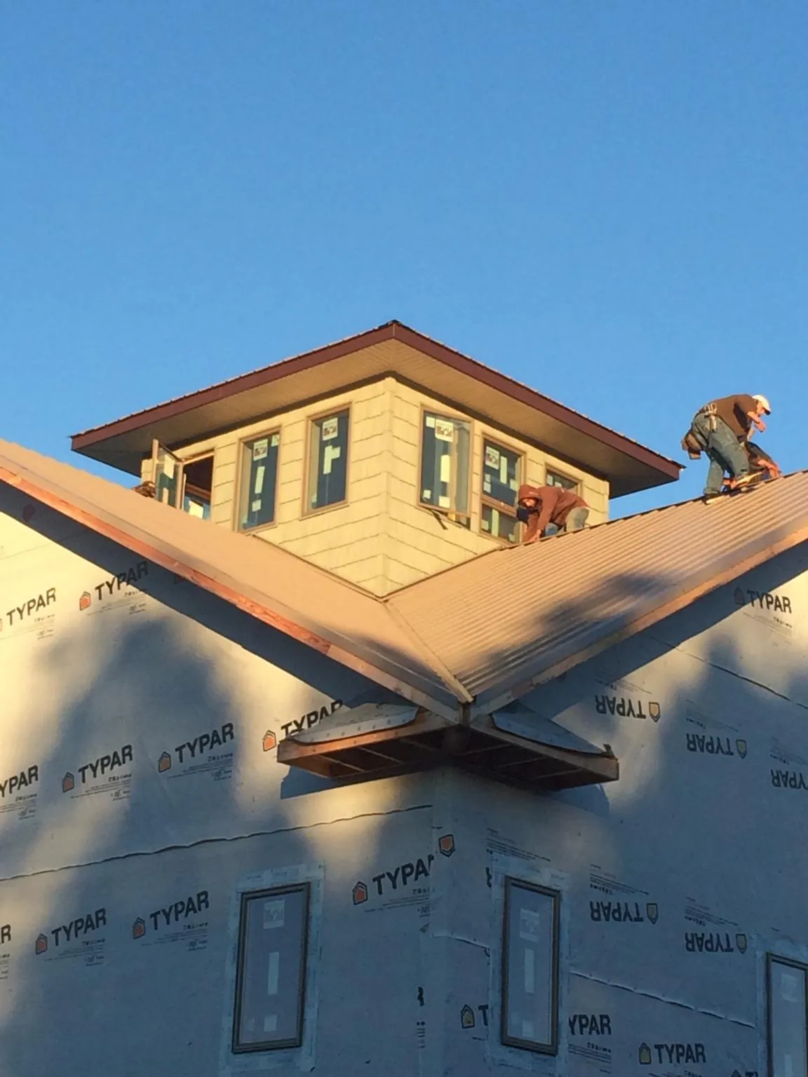 Roofers working around a rooftop cupola on a new metal roof at sunset — Roof Waterproofing in Waynesburg by Roofing Brothers